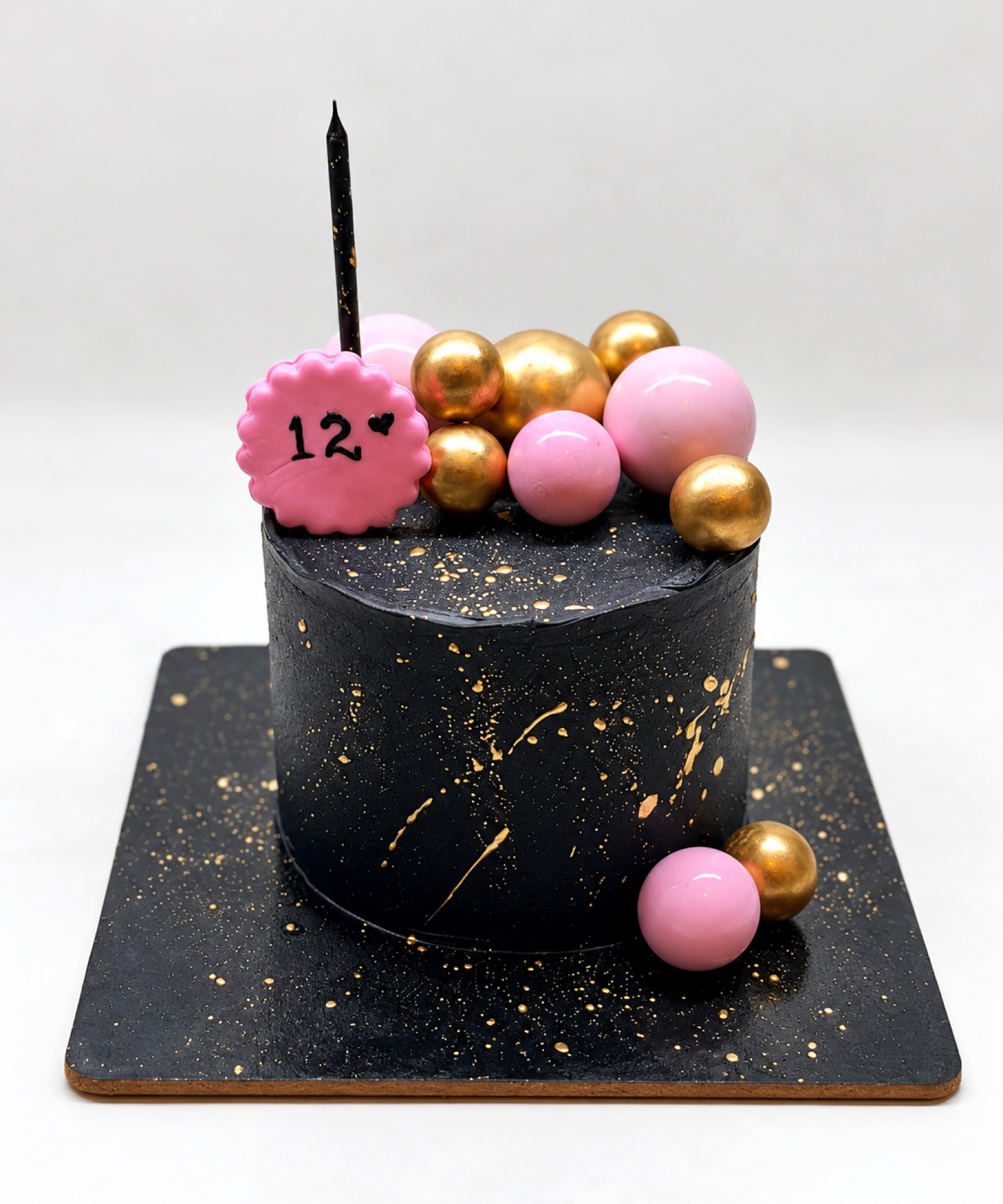 Black celebration cake with pink and gold details